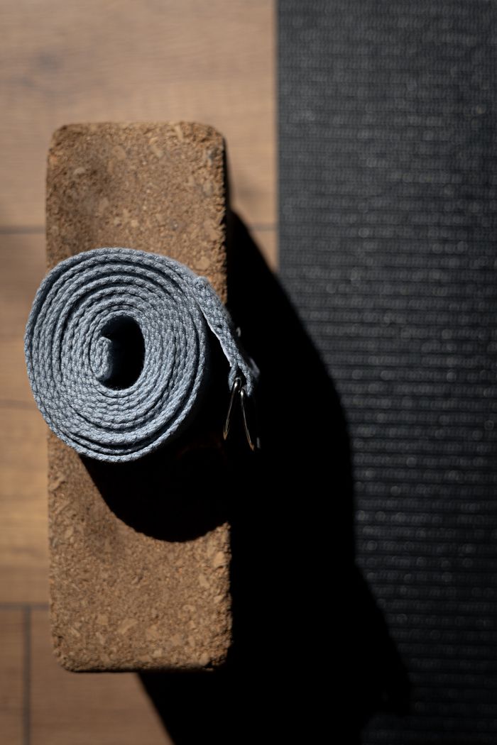 Top view of a yoga strap on a cork block casting a shadow, evoking a minimalist and serene setting.