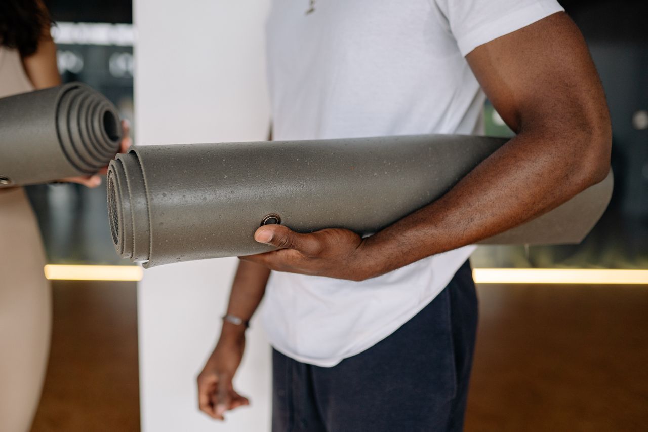 Two adults holding yoga mats in a studio setting, ready for a fitness session.